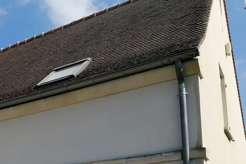Gouttière et descente d’eaux pluviales en zinc posées en rive de toiture, avec leurs colliers de fixation