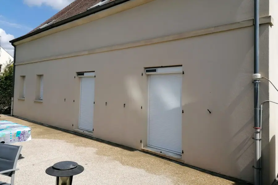 Façade longue après ravalement : enduit de finition uniforme, menuiseries protégées, descente d’eaux pluviales reposée